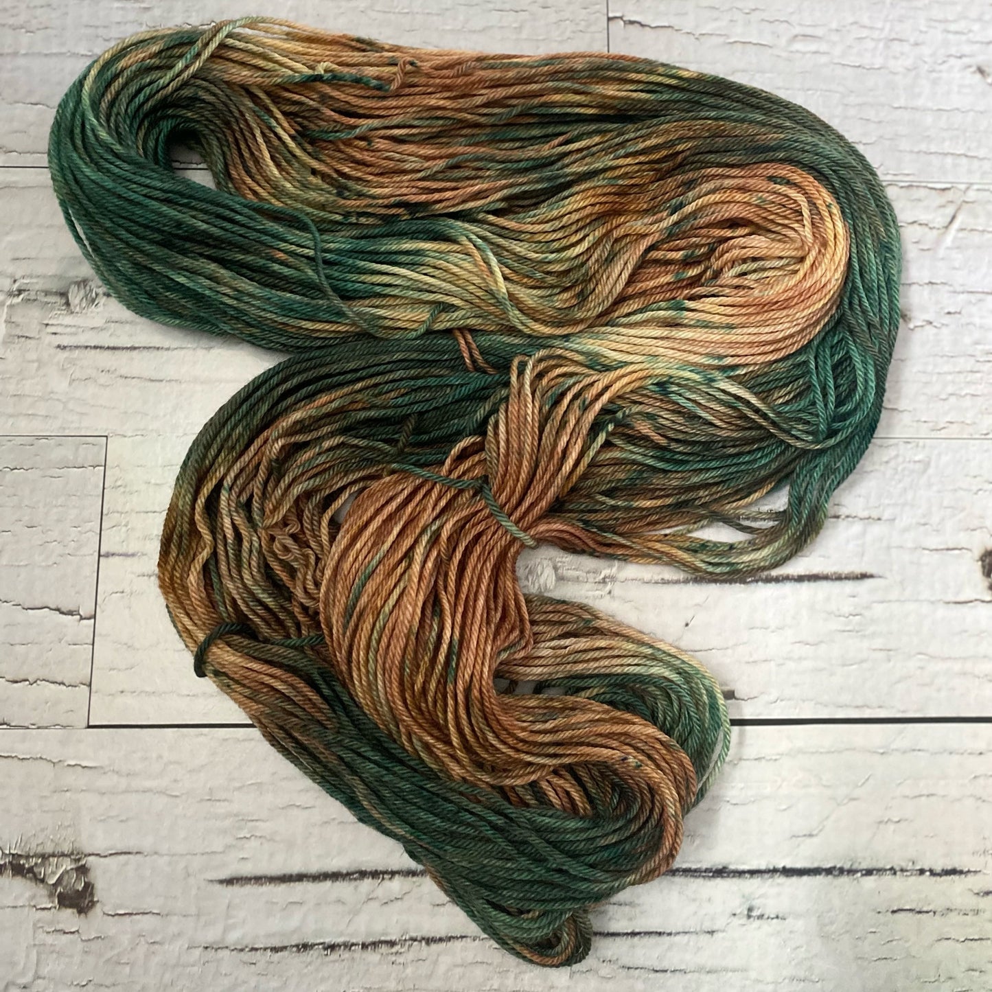 A brown and green variegated hank of yarn laid out.