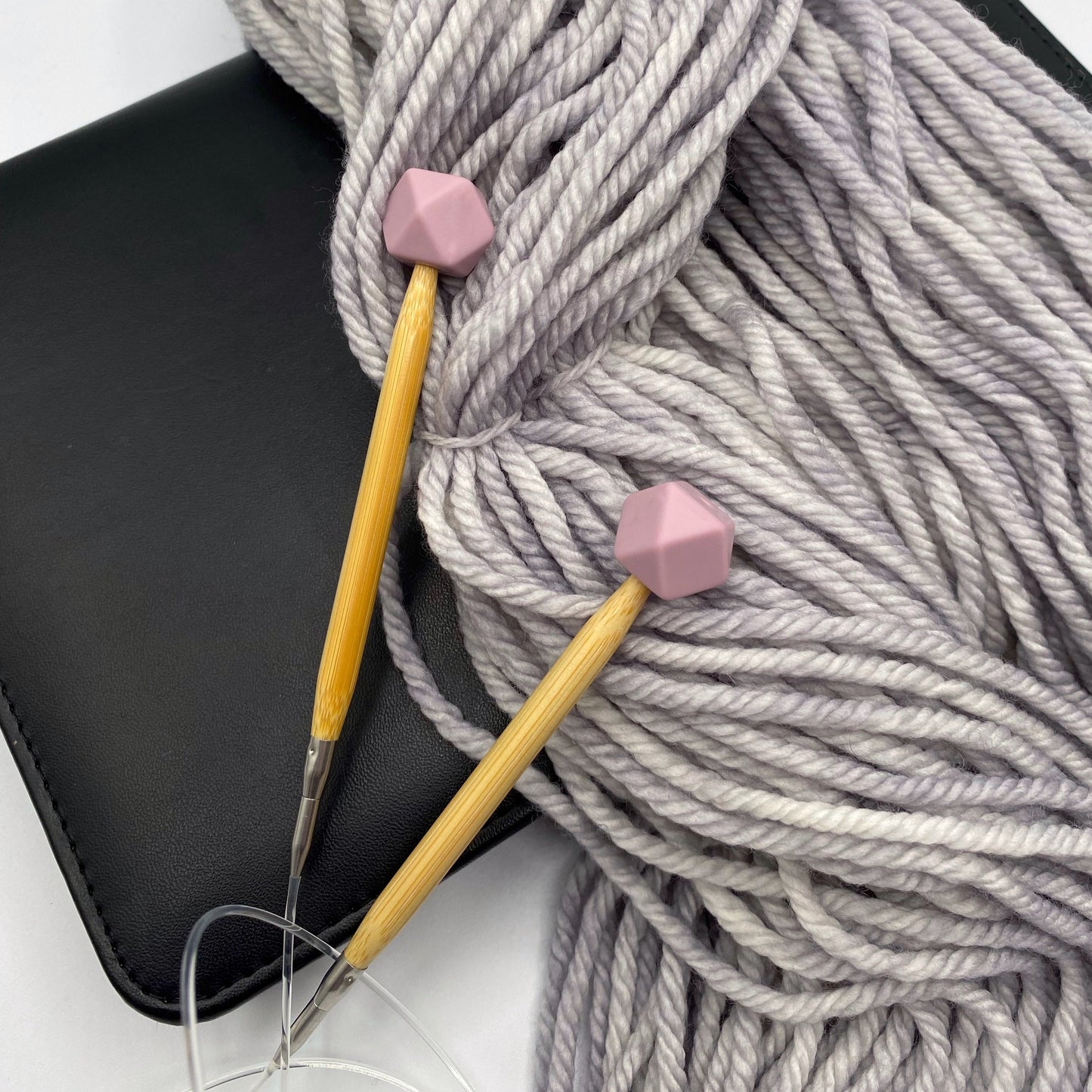a set of knitting needles adorned with mauve hexagon point protectors, laid on top of our Everyday Bulky in Urban.